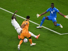 Senegal defender Kalidou Koulibaly (C) fights for the ball with Netherlands forward Cody Gakpo in front of Senegal goalkeeper Edouard Mendy.