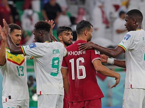 Players react on the pitch after the Qatar 2022 World Cup Group A football match between Qatar and Senegal at the Al-Thumama Stadium.