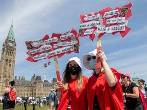 Pro-choice protesters dressed in red robes as characters from The Handmaid's Tale hold signs on Parliament Hill during the National March for Life in Ottawa, Ont., on May 12, 2022.