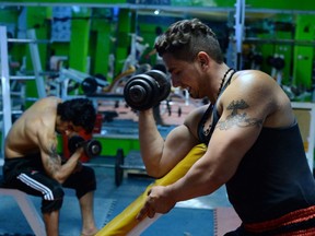 In this photo taken Aug. 7, 2014, Afghan bodybuilder Milad, right, exercises with a dumbbell along with his partner Muzafar, at a bodybuilding gym in Kabul.