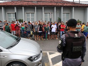 A police officer stands guard as locals gather outside the police station where the perpetrator of two school shootings is being held in Aracruz, Espirito Santo State, Brazil, on Nov. 25, 2022.