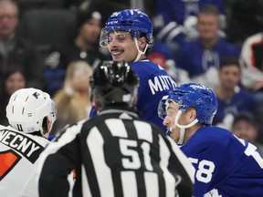 Maple Leafs' Auston Matthews smiles towards Philadelphia Flyers' Travis Konecny  as Michael Bunting moves in quickly during third period NHL hockey action in Toronto on Wednesday, November 2, 2022.