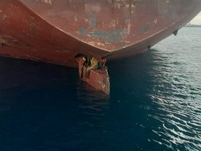 Three stowaway migrants are seen on the rudder blade of petrol vessel Althini II after travelling from Nigeria and before being rescued by Spanish coast guard, in this picture released on the Salvamento Maritimo official Twitter account, at sea near Las Palmas de Gran Canaria port, in the Canary Islands, Spain November 28, 2022.