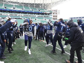 Argonauts linebacker Henoc Muamba picks up head coach Ryan Dinwiddie's son 3-year-old son Lansen on the field during a team walkthrough as they get ready to take on the Winnipeg Blue Bombers at the 109th Grey Cup at Mosaic Stadium.