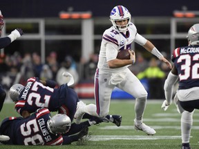 Buffalo Bills quarterback Josh Allen runs with the ball while evading tackles by New England Patriots cornerback J.C. Jackson and inside linebacker Jamie Collins during the second half at Gillette Stadium.