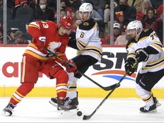 Adam Ruzicka of the Calgary Flames fights for the puck against Mike Reilly and Connor Clifton of the Boston Bruins during the third period of action as the Calgary Flames lost 4-2 to the visiting Boston Bruins at the Saddledome. Saturday, December 11, 2021. Brendan Miller/Postmedia