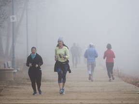 In this Dec. 3, 2017 file photo, runners jog along the foggy boardwalk along Ashbridges Bay Park in Toronto.