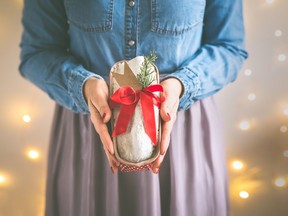 Close up of woman's hands holding homemade stollen christmas cake wrapped as a gift.