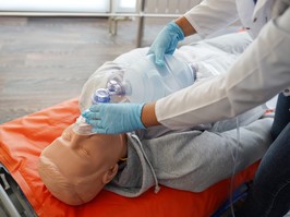 Closeup of nursing student's hands practicing how to provide oxygen administration to a dummy.
