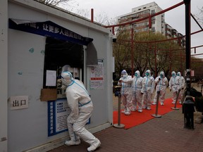 Epidemic-prevention workers in protective suits line up to get swab tested as outbreaks of COVID-19 continue in Beijing, Nov. 28, 2022.