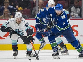 Seattle Kraken forward Shane Wright plays for the puck against Vancouver Canucks forward J.T. Miller in the third period at Rogers Arena. Seattle won 4-3 in overtime.