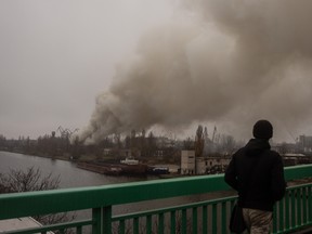 A man looks at smoke rises from a Russian strike in the Kherson shipyards on November 24, 2022 in Kherson, Ukraine.