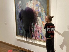 This handout picture released Tuesday, Nov. 15, 2022 by the "Last Generation" shows a climate activist of the "Last Generation" group who has glued himself to the painting "Death and Life" by Austrian artist Gustav Klimt after pouring a black liquid on the artwork at the Leopold Museum in Vienna, Austria.