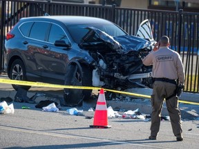 A police officer looks at a damaged vehicle after multiple Los Angeles County Sheriff's Department recruits were injured when a car crashed into them while they were out for a run in Whittier, Calif., Wednesday, Nov. 16, 2022.