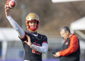 Arnaud Desjardins, starting quarterback for the Laval Rouge et Or, keeps his arm warm Thursday as head coach Glen Constantin looks on in the background. Laval and the Saskatchewan Huskies meet in London at Alumni Field Saturday for the Vanier Cup. (Mike Hensen/The London Free Press)