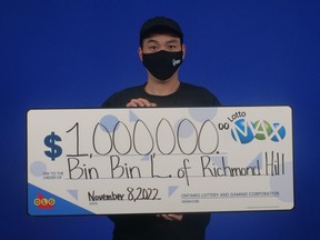 Man wearing a face mask holding large cheque for $1 million.