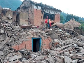 People stand outside the ruins of collapsed houses after an earthquake struck early Wednesday, in the western district of Doti, Nepal Nov. 9, 2022.
