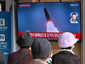 People watch a TV screen showing a news broadcast with file footage of a North Korean missile test, at a railway station in Seoul, Oct. 28, 2022.