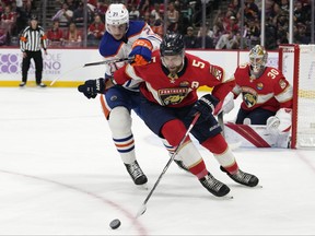 Edmonton Oilers center Klim Kostin (21) and Florida Panthers defenseman Aaron Ekblad (5) chase the puck during the first period of an NHL hockey game, Saturday, Nov. 12, 2022, in Sunrise, Fla.