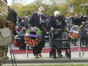 Ret.  Maj. Gen. Dave Fraser, former Canadian Forces commander in Afghanistan (left) helps 100-year old Second World War veteran Marvin Gord lay the Year of the Poppy wreath during the Remembrance Day ceremony at the Old City Hall cenotaph in Toronto on Nov. 11, 2021.