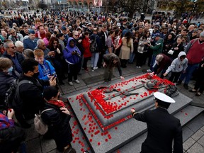 People place poppies on the Tomb of the Unknown Soldier after the memorial service at the National War Memorial in Ottawa on Friday, November 11, 2022.