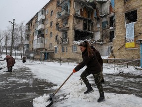 Tetiana Reznychenko, a resident of the Ukrainian village of Horenka, shovels snow near her apartment building, which has no electricity, heating or running water after being heavily damaged in the early days of the Russian invasion, November 19, 2022.