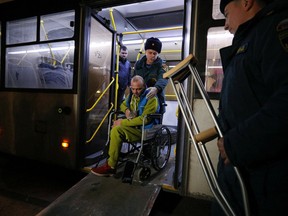 Members of the Russian Emergencies Ministry help a wheelchair user, who was evacuated from the Russian-controlled part of Kherson region of Ukraine, to leave a bus upon arrival at a local railway station in the town of Dzhankoi, Crimea, Nov. 10, 2022.