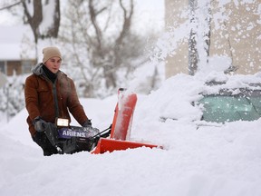 Man uses a snow blower to dig out a vehicle on the street during a snowstorm as extreme winter weather hits Buffalo, New York, U.S., November 18, 2022.