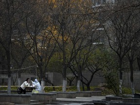 A worker in protective suit collects a sample from a woman at a coronavirus testing site setup inside a residential compound in Beijing, Thursday, Nov. 24, 2022.