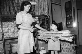 In this file photo taken on Nov. 24, 1949, a little boy buys baguette bread, as Parisians stock up on bread for two days in preparation for the general bakers’ strike in Paris.