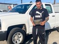 Man posing in front of new white pickup truck.