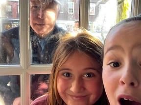 U.S. President Joe Biden looks through window to pose for selfie with two girls.