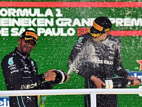 Lewis Hamilton (left) and winner George Russell celebrate with champagne on the podium of the Formula One Brazil Grand Prix, in Sao Paulo, Brazil, on November 13, 2022.