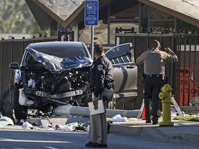 Two investigators stand next to a mangled SUV that struck Los Angeles County sheriff's recruits in Whittier, Calif., Wednesday, Nov. 16, 2022.