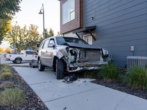 SUV with extensive damage to its front on sidewalk next to residence.