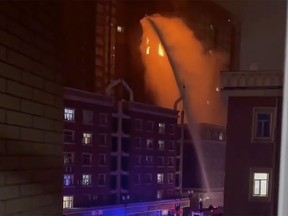 In this image taken from video, firefighters spray water on a fire at a residential building in Urumqi in western China's Xinjiang Uyghur Autonomous Region, Thursday, Nov. 24, 2022.