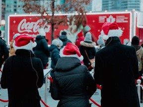 Backs of three carollers with Coca-Cola truck in front of them.
