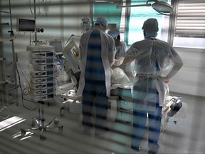 Health workers attend a patient infected with COVID-19 at the intensive care unit for patients infected with the COVID of the Timone hospital, in Marseille, southern France on Jan. 5, 2022.