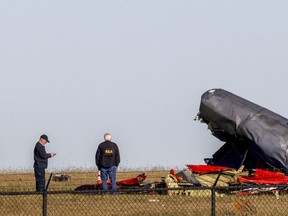 Officials, including those from the Federal Aviation Administration, survey damage from Saturday's crash of a Boeing B-17 Flying Fortress and a Bell P-63 Kingcobra at Dallas Executive Airport on Sunday, Nov. 13, 2022, in Dallas.