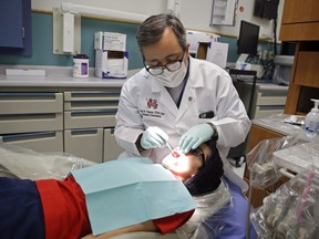 A dentist checks the teeth of Justin Perez, 11, during an office visit Friday, Jan. 22, 2016.