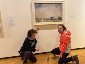 This photo provided to media from the group Stop Fracking Around shows Erin Fletcher, left, and Emily Kelsall, right, in front of the Emily Carr painting, Stumps and Sky, at the Vancouver Art Gallery on Saturday, Nov. 12, 2022.