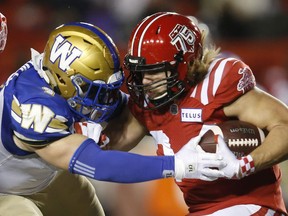 Winnipeg Blue Bombers' Adam Bighill stops Calgary Stampeders' Ante Milanovic-Litre during the second half of their CFL football game in Calgary, Saturday, Nov. 20, 2021. Bighill has signed a two-year contract extension with the Winnipeg Blue Bombers.