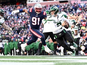 New York Jets quarterback Zach Wilson runs with the ball under pressure from New England Patriots defensive end Deatrich Wise Jr. during the second half at Gillette Stadium.