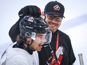 Canada's National Junior Team assistant coach Dennis Williams pats defenceman Daemon Hunt on the helmet during a training camp practice in Calgary, Tuesday, Aug. 2, 2022.THE CANADIAN PRESS/Jeff McIntosh
