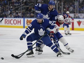Toronto Maple Leafs defenseman Mac Hollowell (81) tries to control the puck as forward Ilya Mikheyev (65) blocks out Montreal Canadiens forward Mathieu Perreault (85) during the second period at Scotiabank Arena.