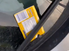 A screengrab from video of a Juicy Fruit package left under the windshield of a car.