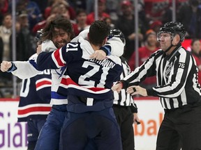Tampa Bay Lightning left wing Pat Maroon, left, fights with Washington Capitals right wing Garnet Hathaway as linesman Michel Cormier, right, tries to separate them in the second period of an NHL hockey game, Friday, Nov. 11, 2022, in Washington.