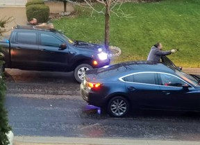 Two men, believed to be a York Regional Police plainclothes officers, points what appear to be handguns during an encounter in Markham where one male suspect was shot dead and another injured.