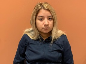 Blonde woman in black shirt sitting against orange wall