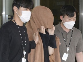 A woman, centre, leaves the Seoul Central District Prosecutors' Office at Ulsan Jungbu police station in Ulsan, South Korea, Sept. 15, 2022. A South Korean court has approved the extradition of the 42-year-old woman facing murder charges in New Zealand over her possible connection to the bodies of two long-dead children found abandoned in suitcases in August.